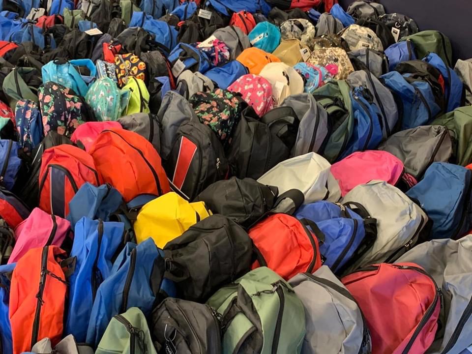 Overhead view of a sea of brand-new backpacks in every color filling the staging room