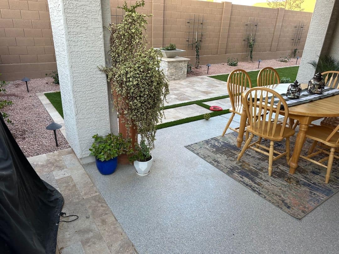 Covered patio in a Peoria backyard with a flake-coat concrete floor, opening onto a travertine courtyard and water feature