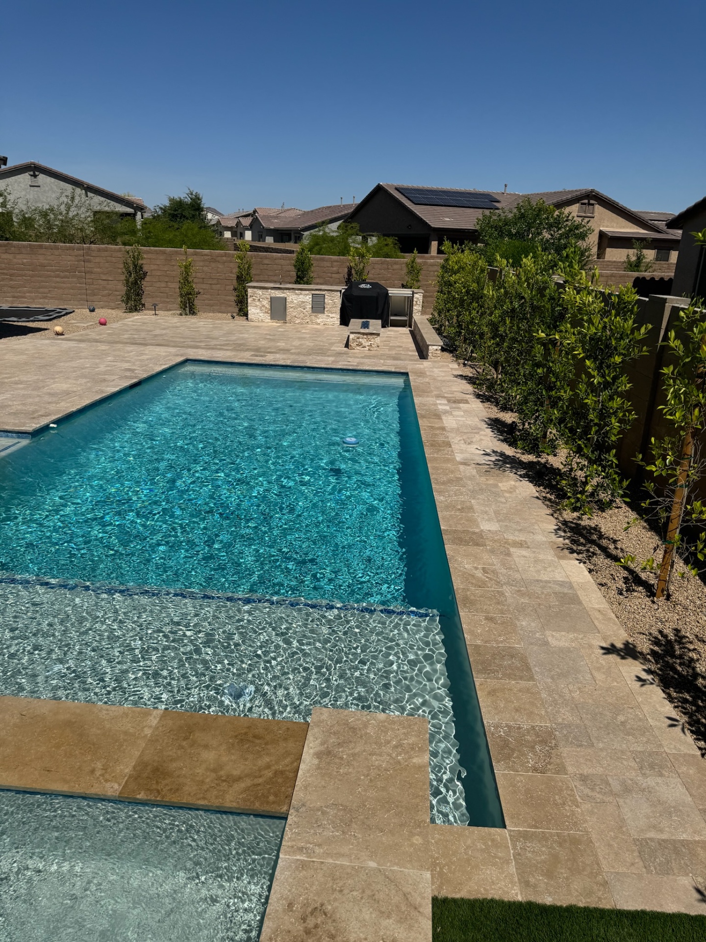 Peoria custom pool with baja shelf, glass-tile waterline, travertine paver deck and outdoor kitchen