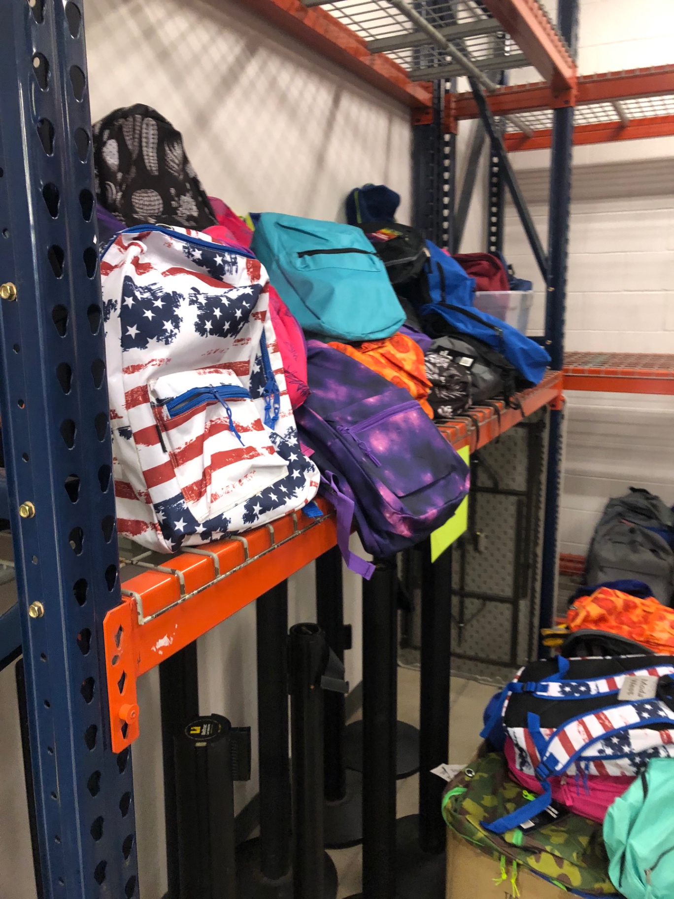 Specialty backpacks including an American flag print and galaxy print on warehouse shelving