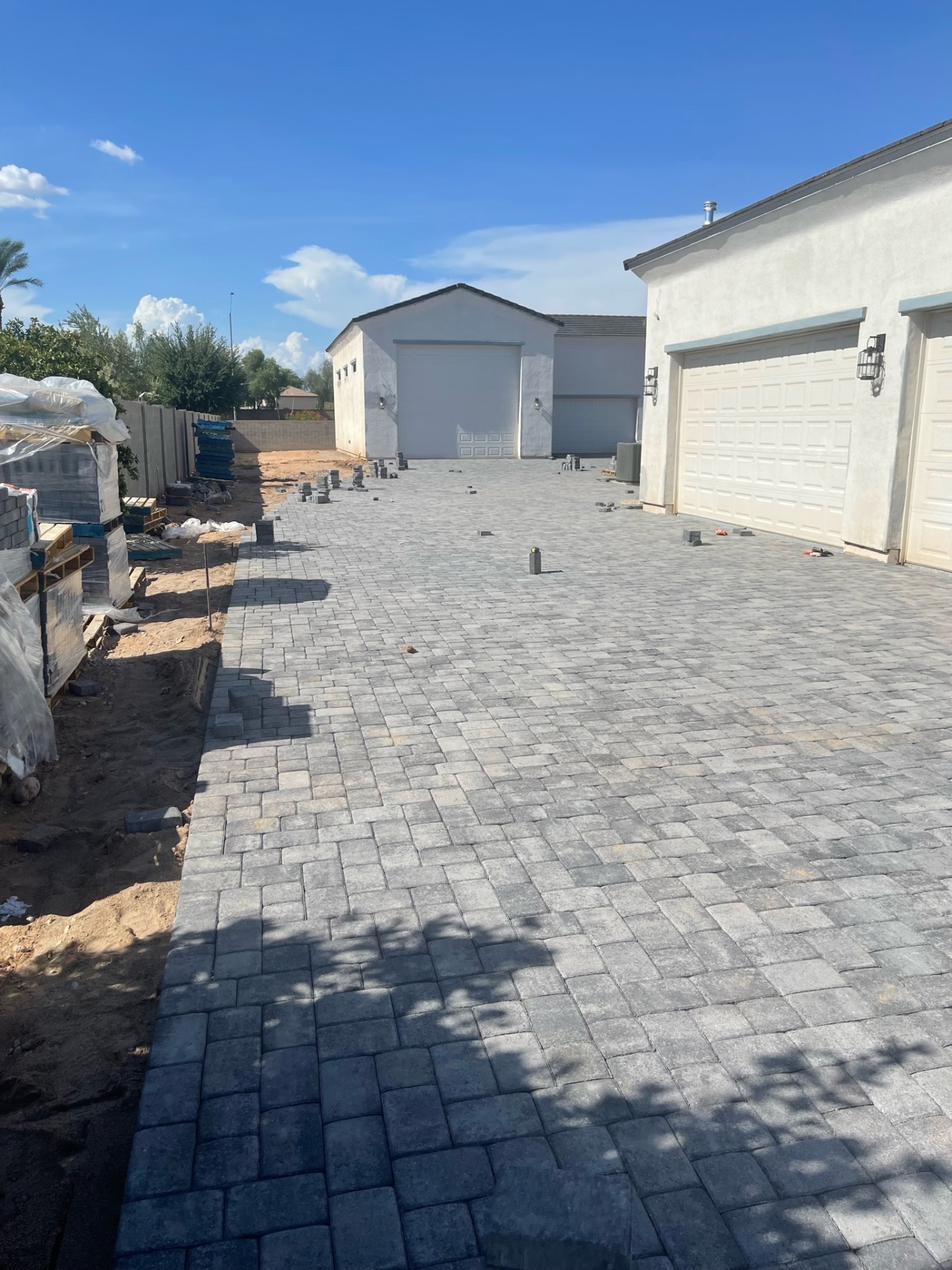 Waddell (Surprise-area) wide charcoal paver driveway between three-car garage and detached RV garage laid in running-bond field with soldier-course border by AE Outdoor Living