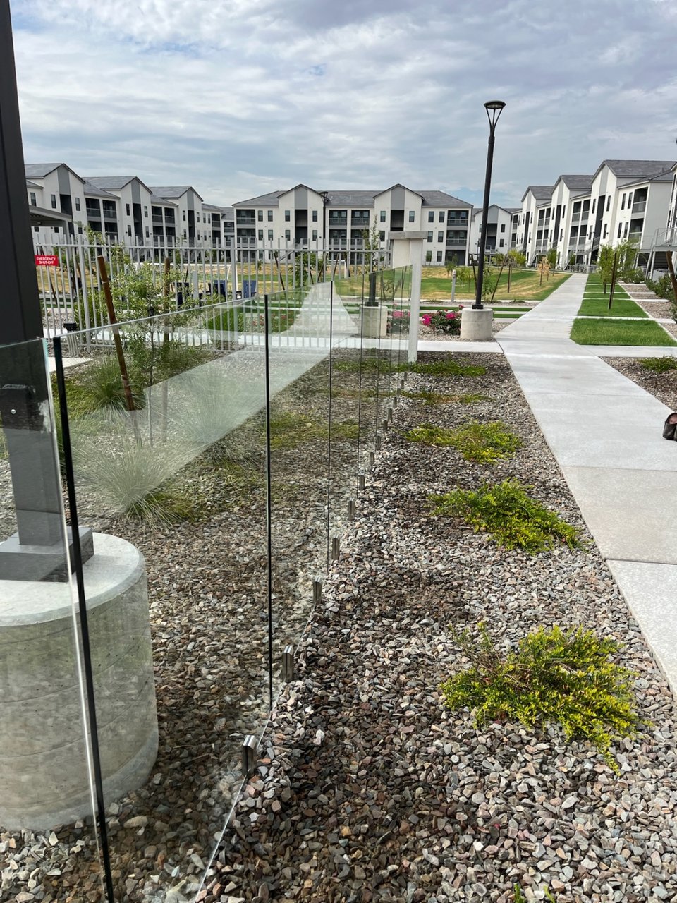 Line of frameless glass fence panels bordering a multifamily pool area, with open sightlines across the amenity deck.