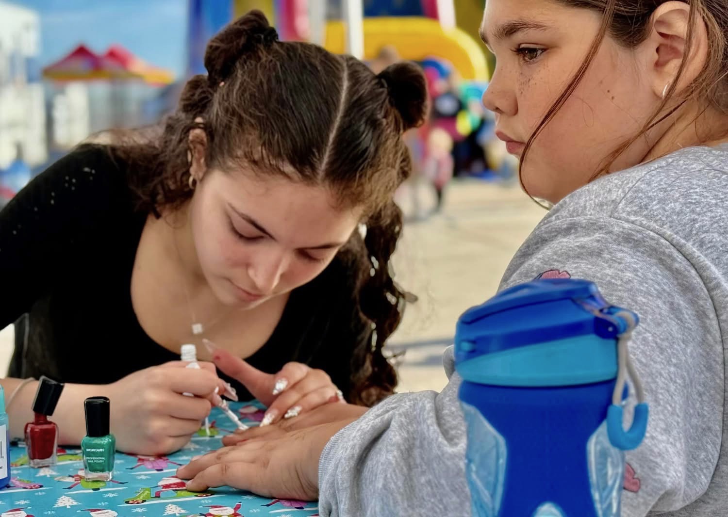 Volunteer doing nails for a young guest at A Day of Giving 2025