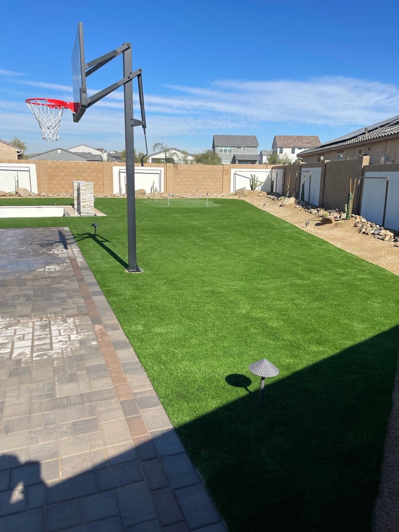 Goodyear backyard artificial turf lawn with in-ground basketball hoop, paver sport court and putting green