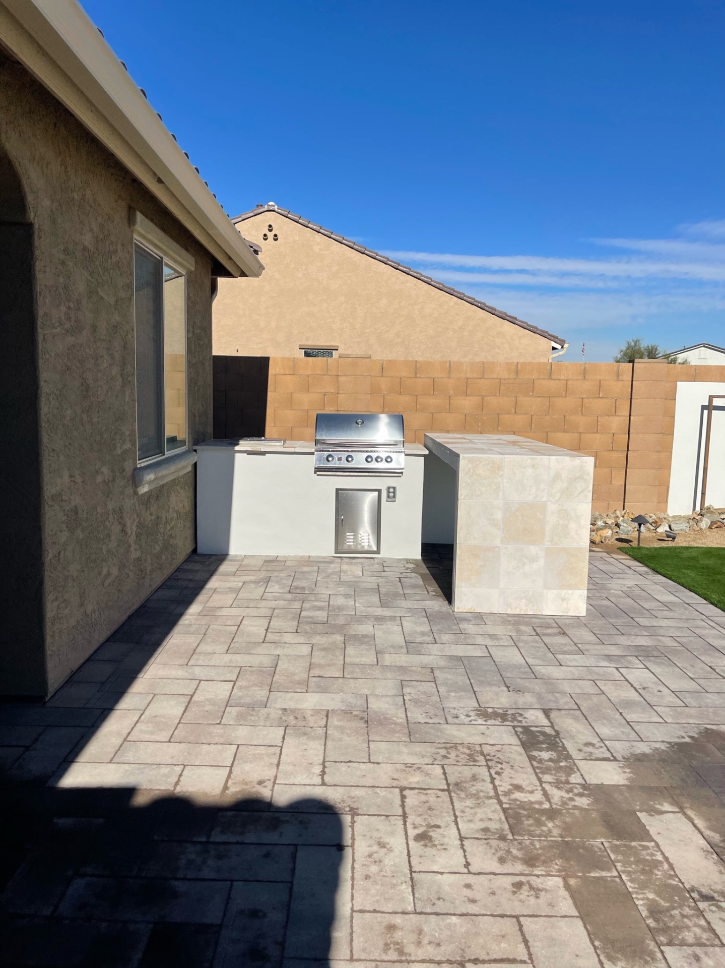 Goodyear paver patio with built-in stucco BBQ island, travertine-tile bar counter and stainless grill by AE Outdoor Living