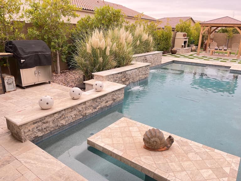 Vask residence The Meadows Peoria AZ pool with stacked-stone spillway wall, travertine coping and deck, in-pool tanning ledge, and pampas grass