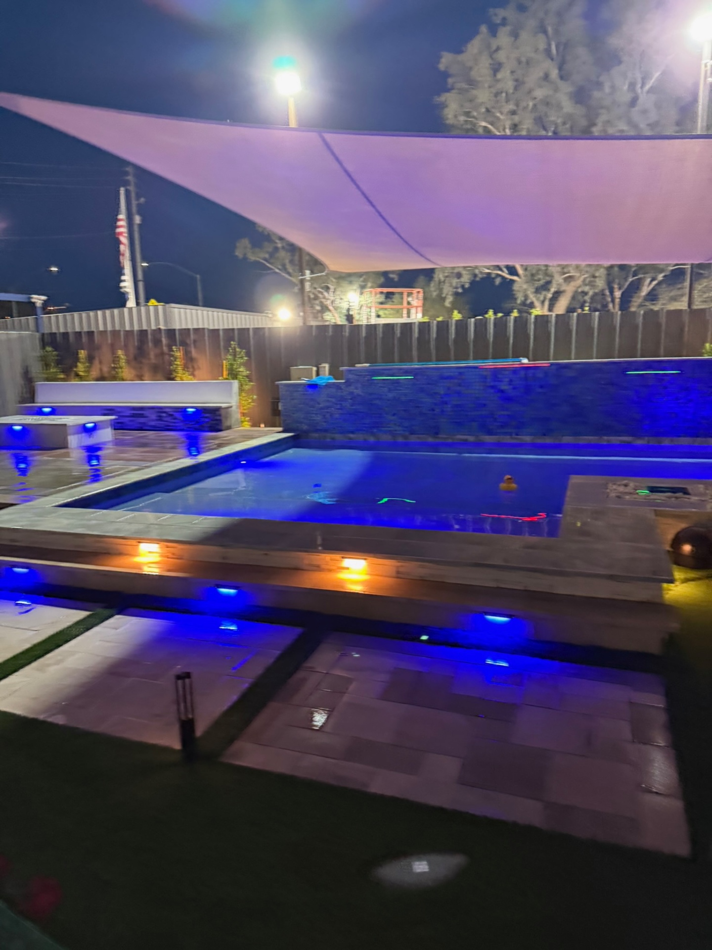Square display pool with blue LED step lighting and sail shade