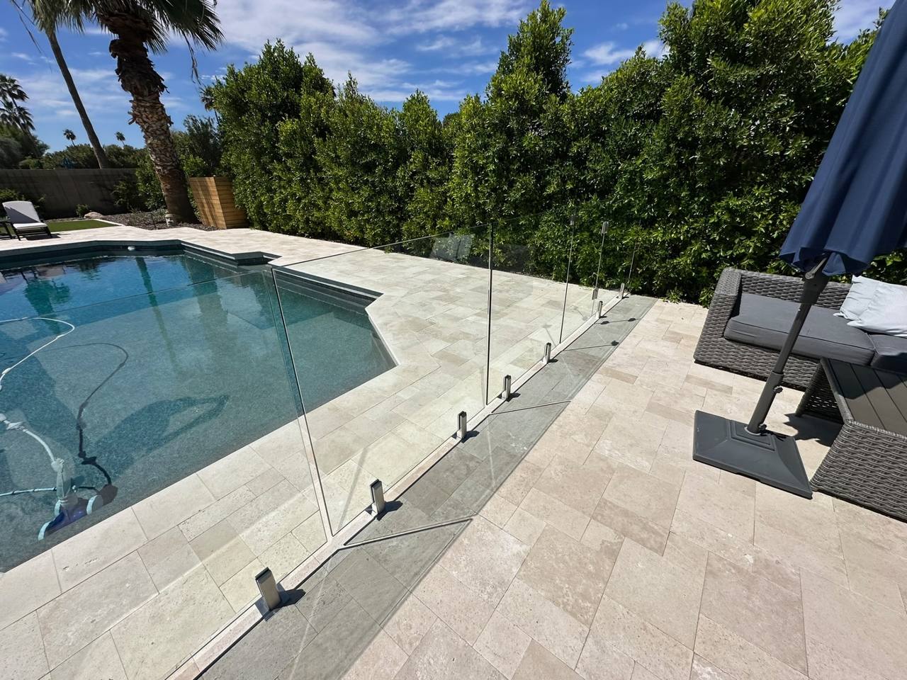 Frameless Sonoran Glass pool fencing around a travertine pool deck