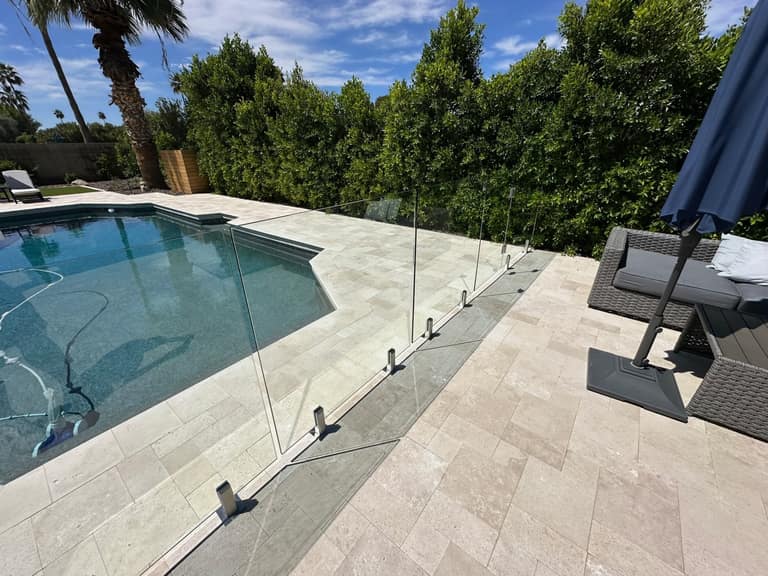 Frameless Sonoran Glass pool fencing around a travertine pool deck