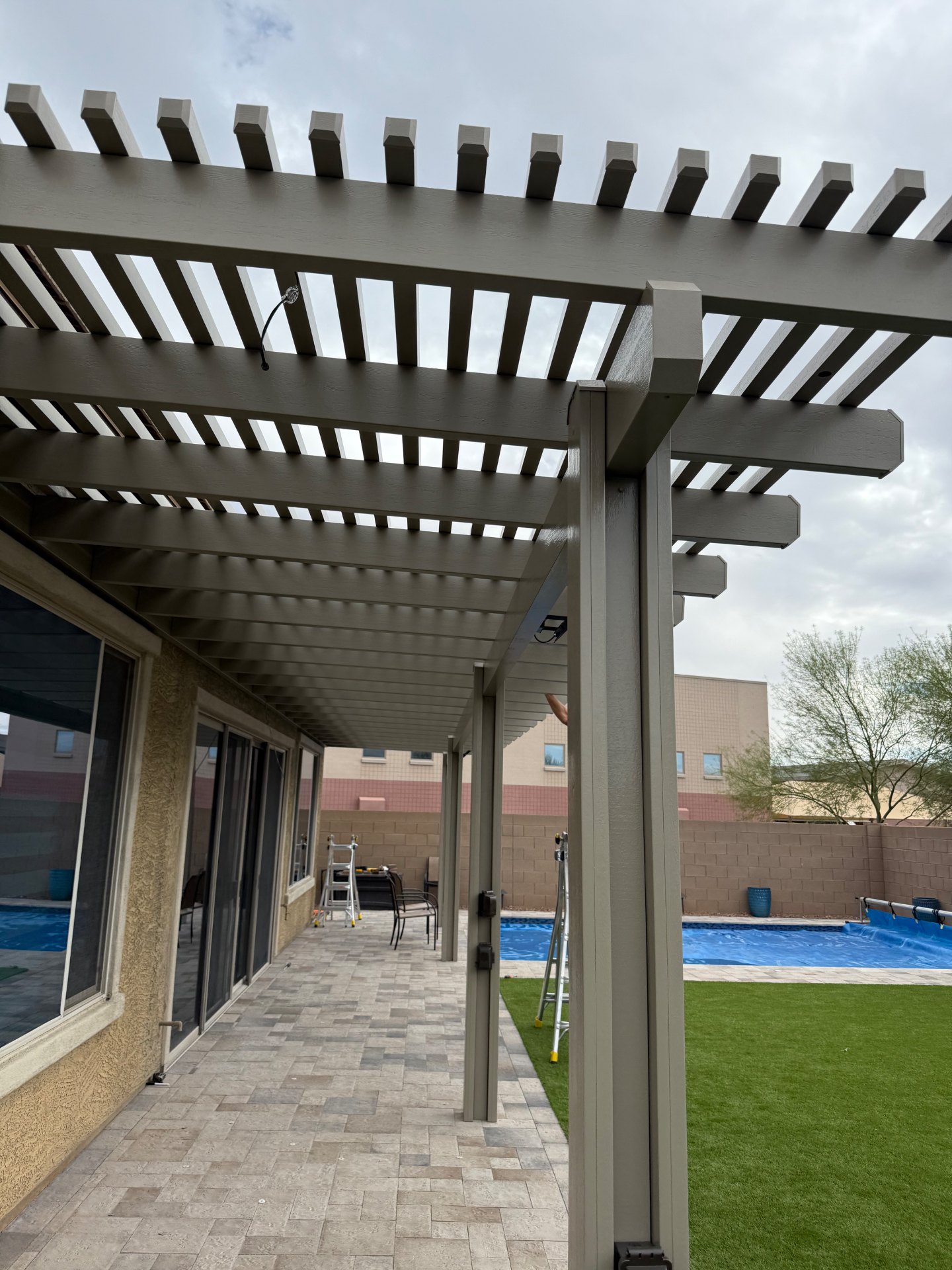 Long-run white aluminum pergola showing precise member spacing and clean poolside integration.