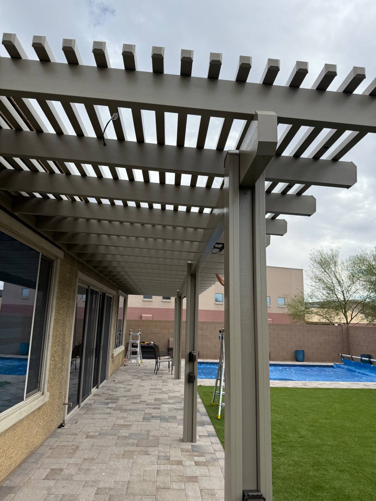 Long-run white aluminum pergola showing precise member spacing and clean poolside integration.