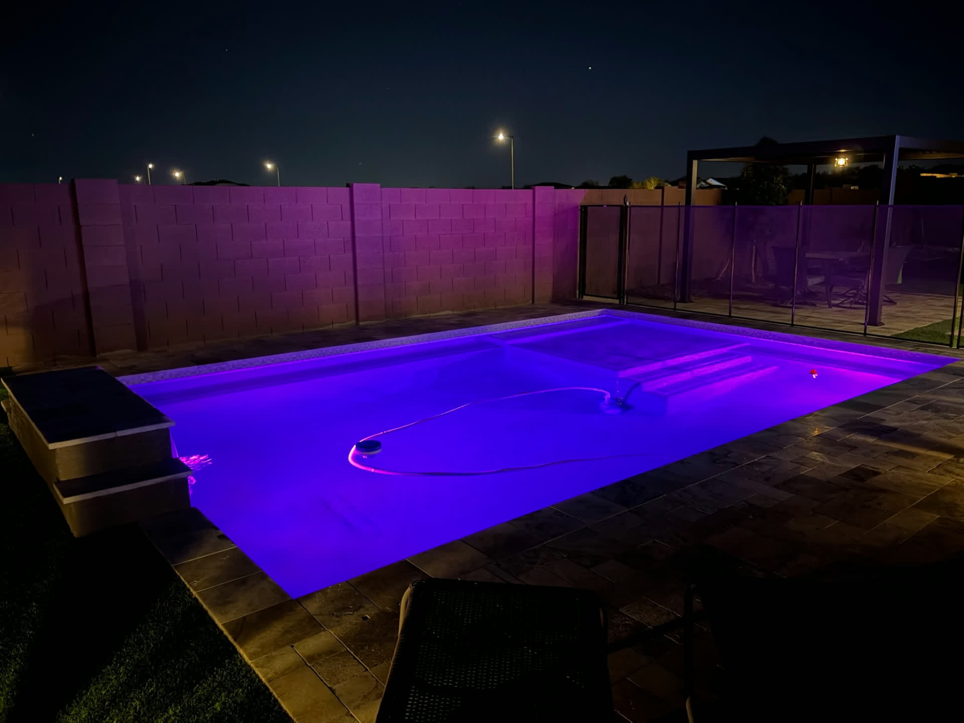 Purple pool lighting with glass fencing in the background.