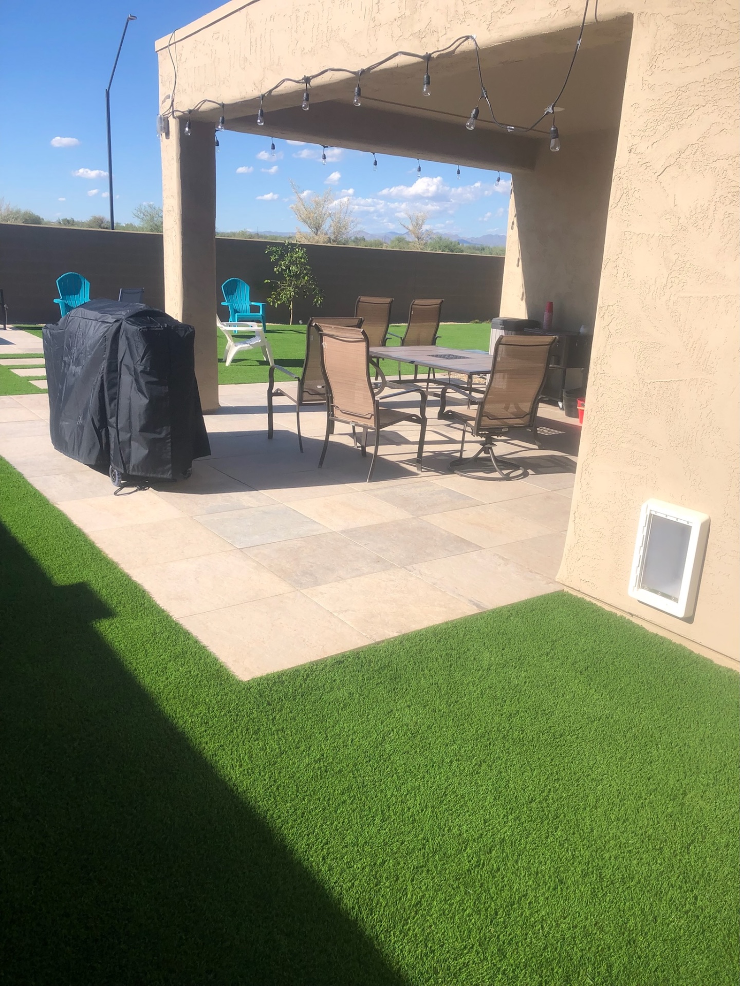 Buckeye travertine paver patio under covered ramada with artificial turf edge