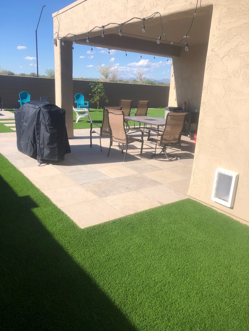 Buckeye travertine paver patio under covered ramada with artificial turf edge