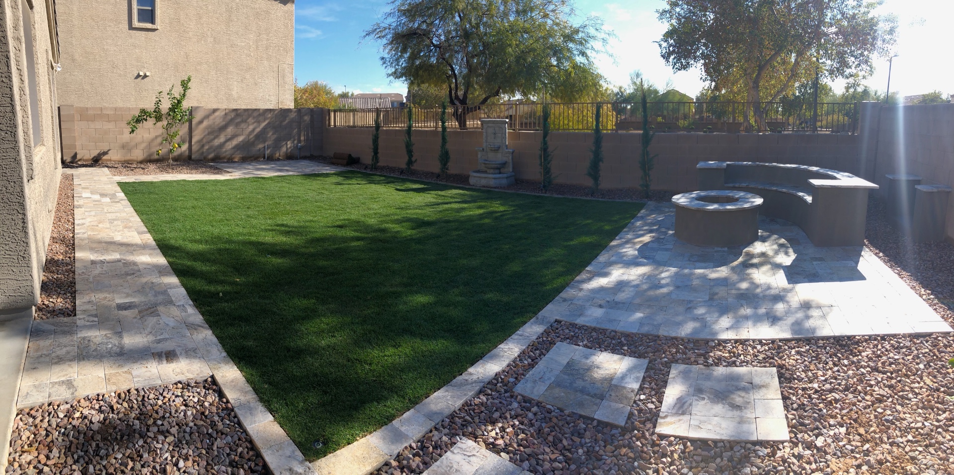 Verrado backyard turf lawn framed by travertine paver borders and stepping stones