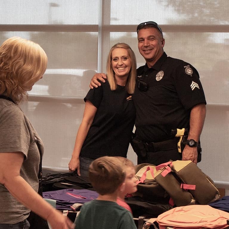 AE Outdoor Living team member posing with a Peoria police officer during the backpack drive