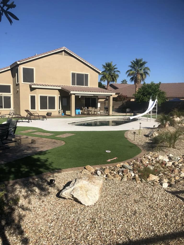 Glendale backyard with artificial turf, paver hardscape, desert rock and low-voltage lights around a pool.