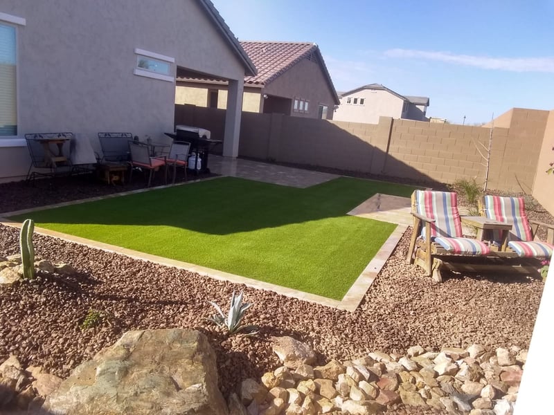 Verrado backyard turf lawn tied into a paver patio with rock border and desert plantings