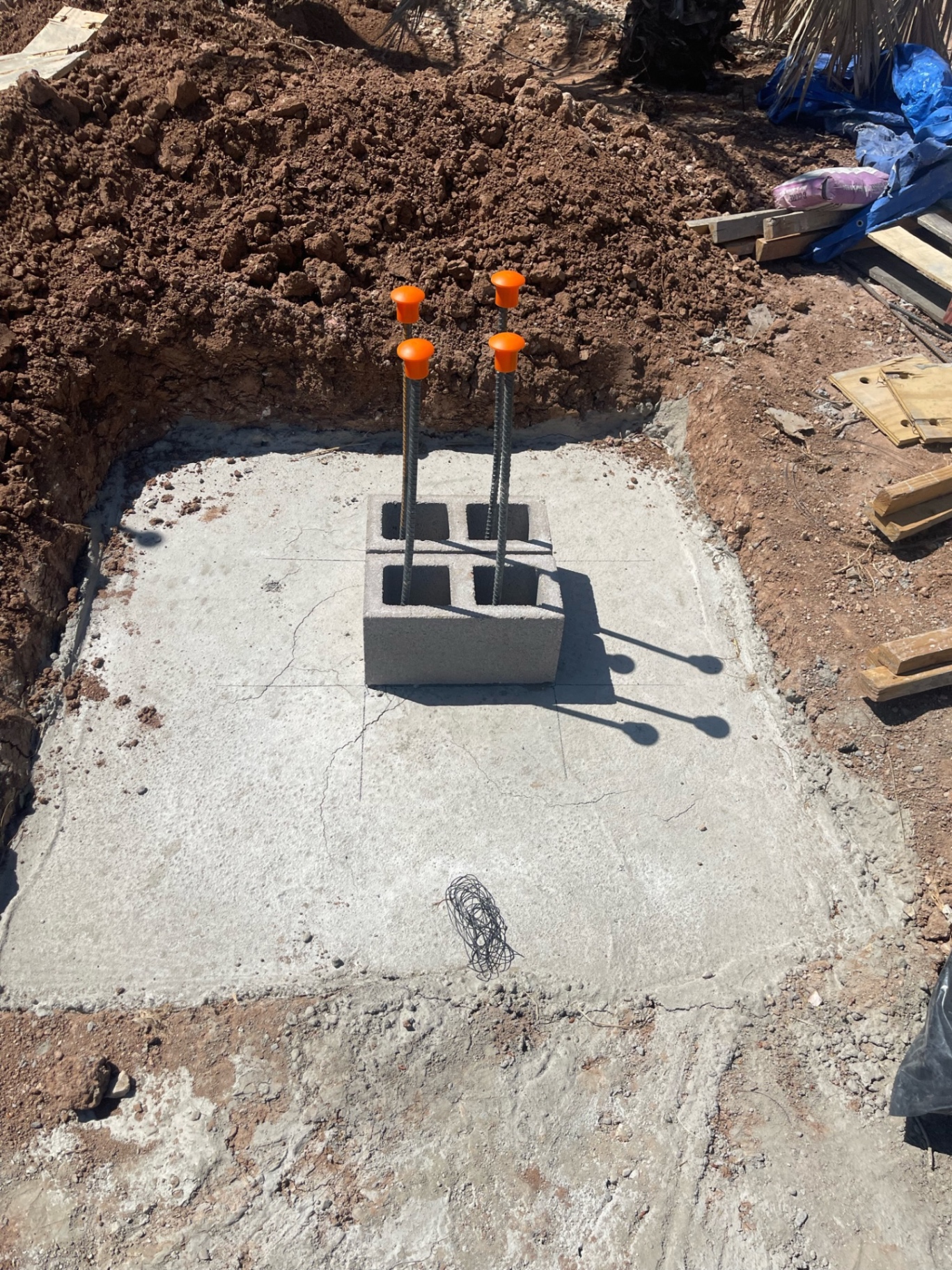 Square concrete pier pad with four capped rebar dowels centered through a CMU block starter