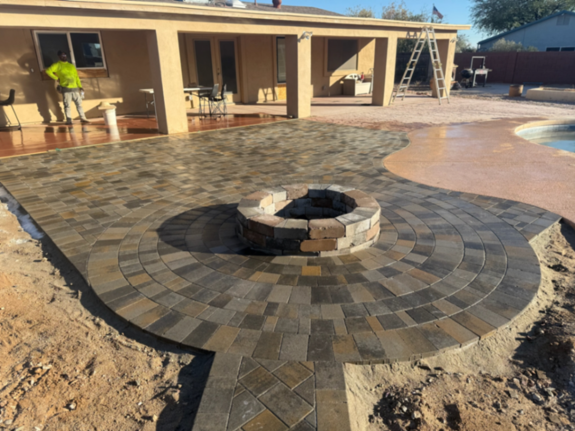 Circular paver patio built around a masonry fire pit, tying the covered patio to the pool deck.