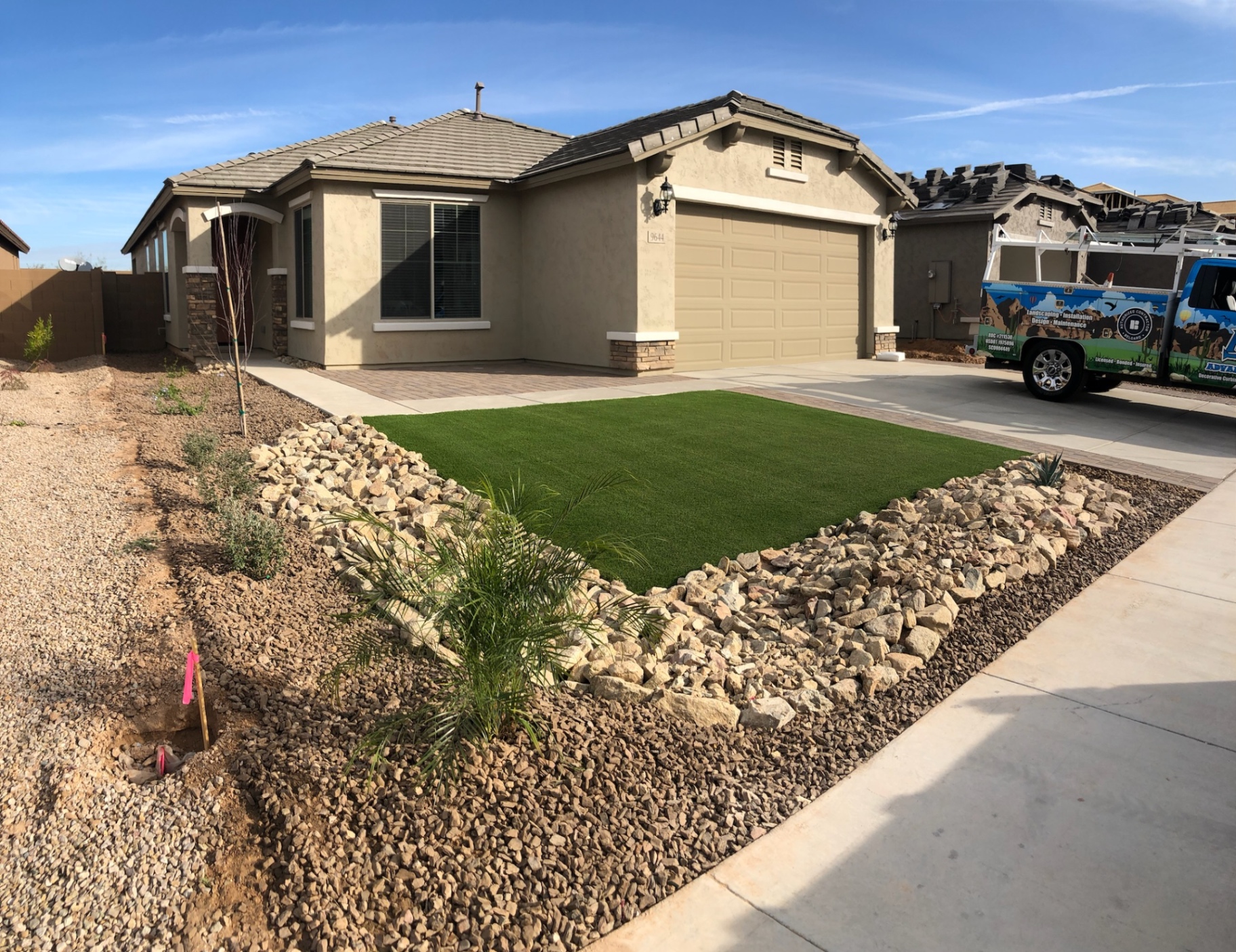 Verrado front yard driveway paver ribbon with artificial turf and desert-scape rock border by AE Outdoor Living