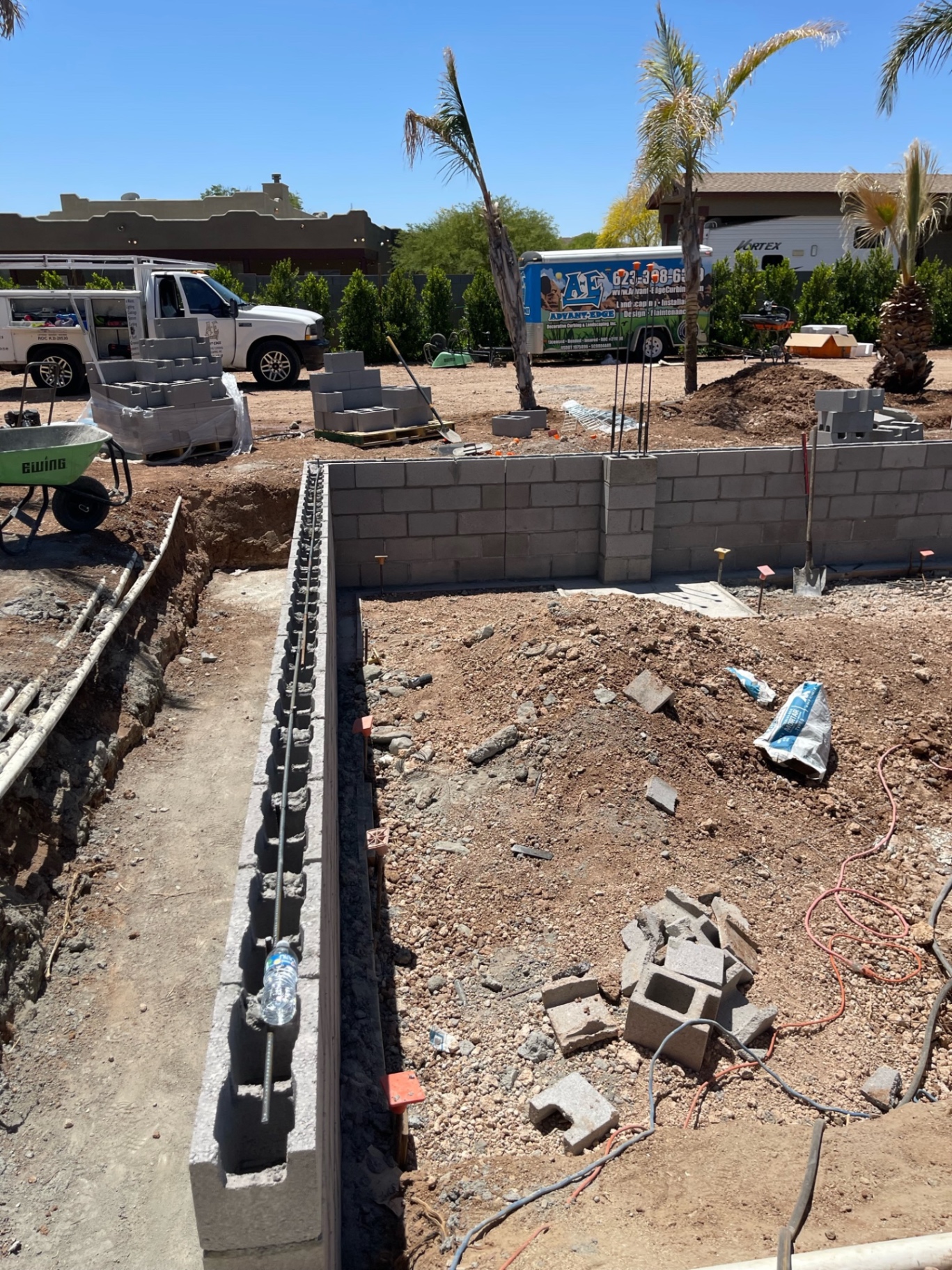 Early CMU block walls under construction with AE Advant-Edge trucks and trailer staged on the open dirt jobsite