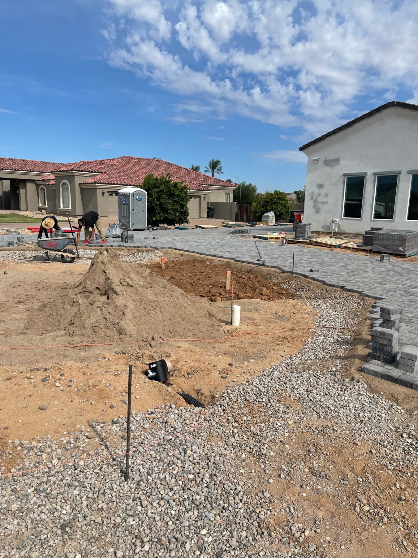 Waddell (Surprise-area) paver install in progress with sand base staged for pool shell area, compacted ABC and edge-course pavers curving around future pool by AE Outdoor Living