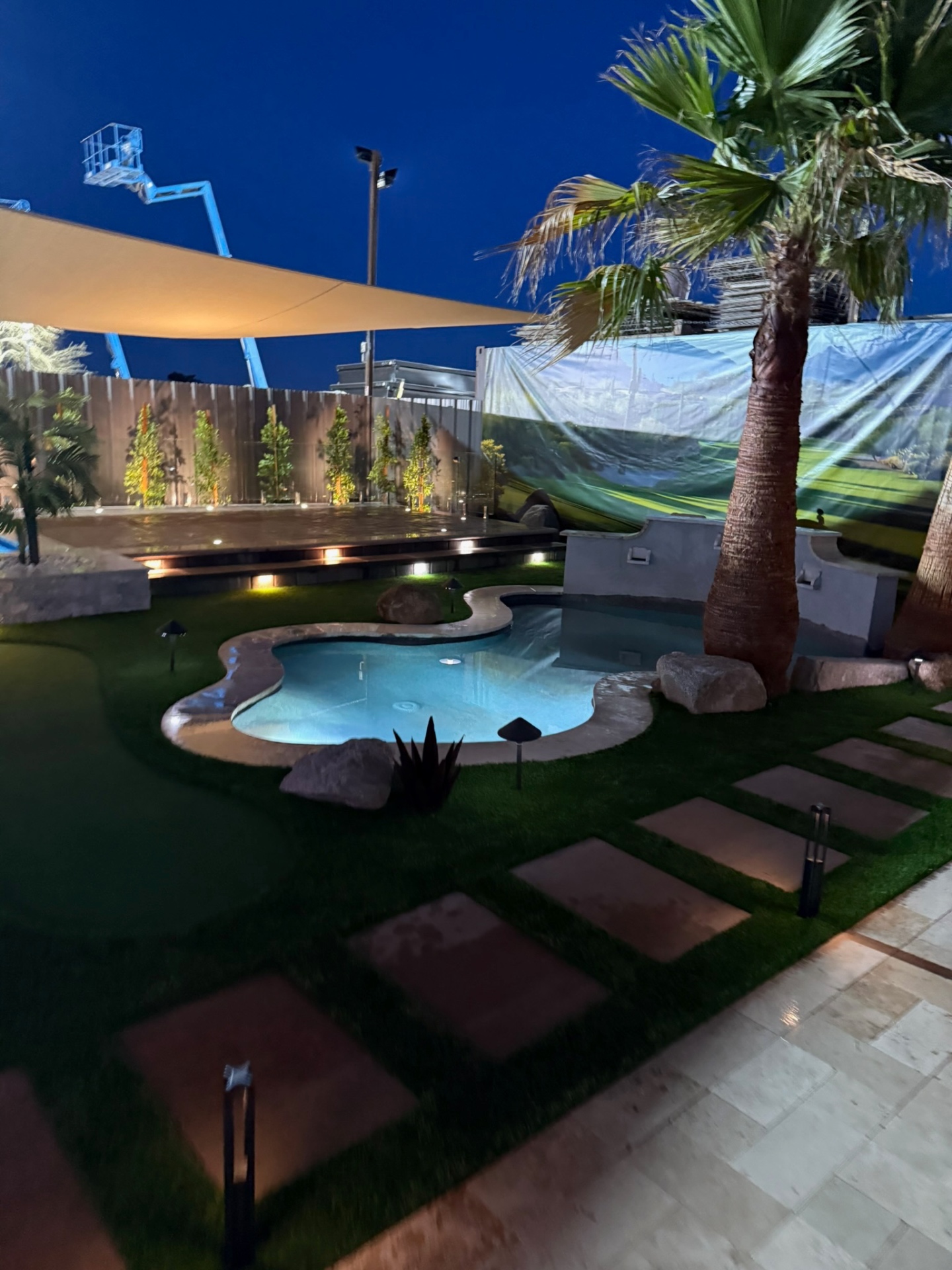 Mini display pool with travertine coping and putting green at dusk