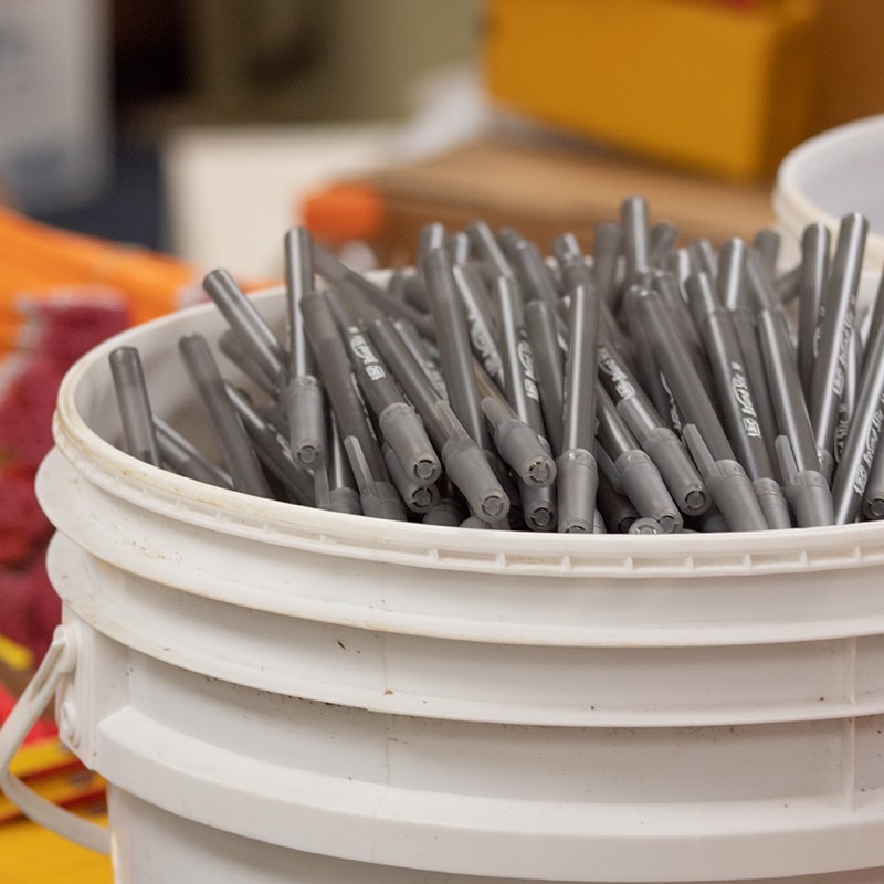 Five-gallon bucket filled with hundreds of gray Bic pens ready for distribution