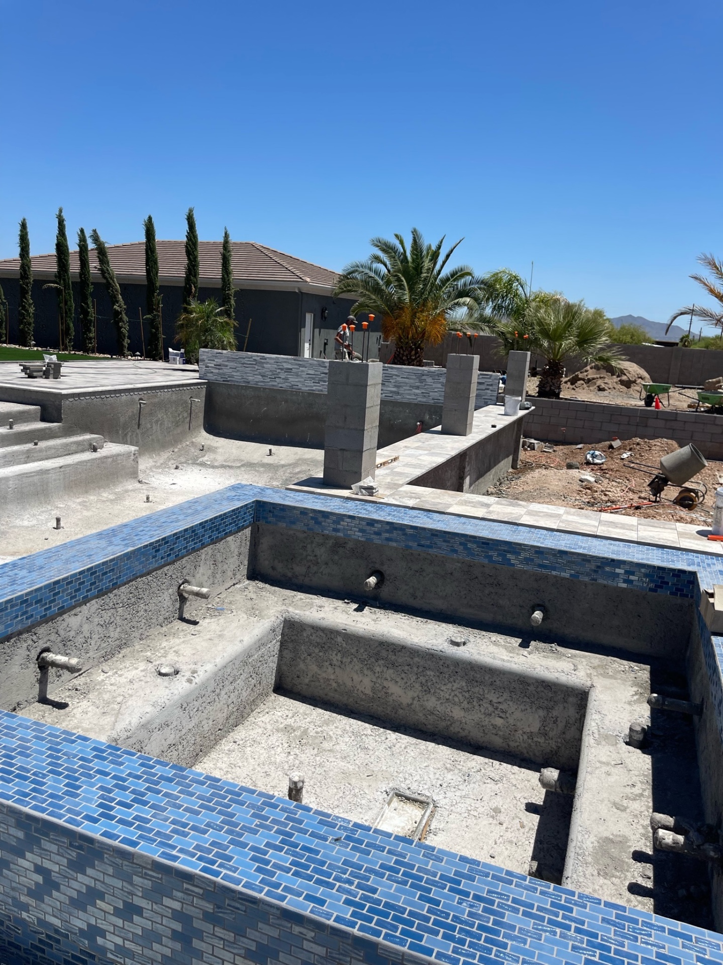 Raised blue-tiled spa and pool shell with structural walls and unfinished deck area stretching toward the far boundary