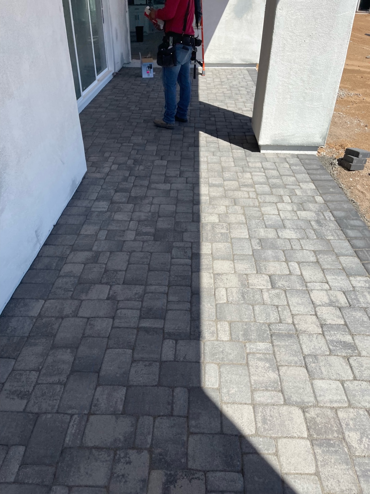 Waddell (Surprise-area) covered patio paver install with two-tone charcoal and grey field pattern running from the sliding door out to the yard by AE Outdoor Living