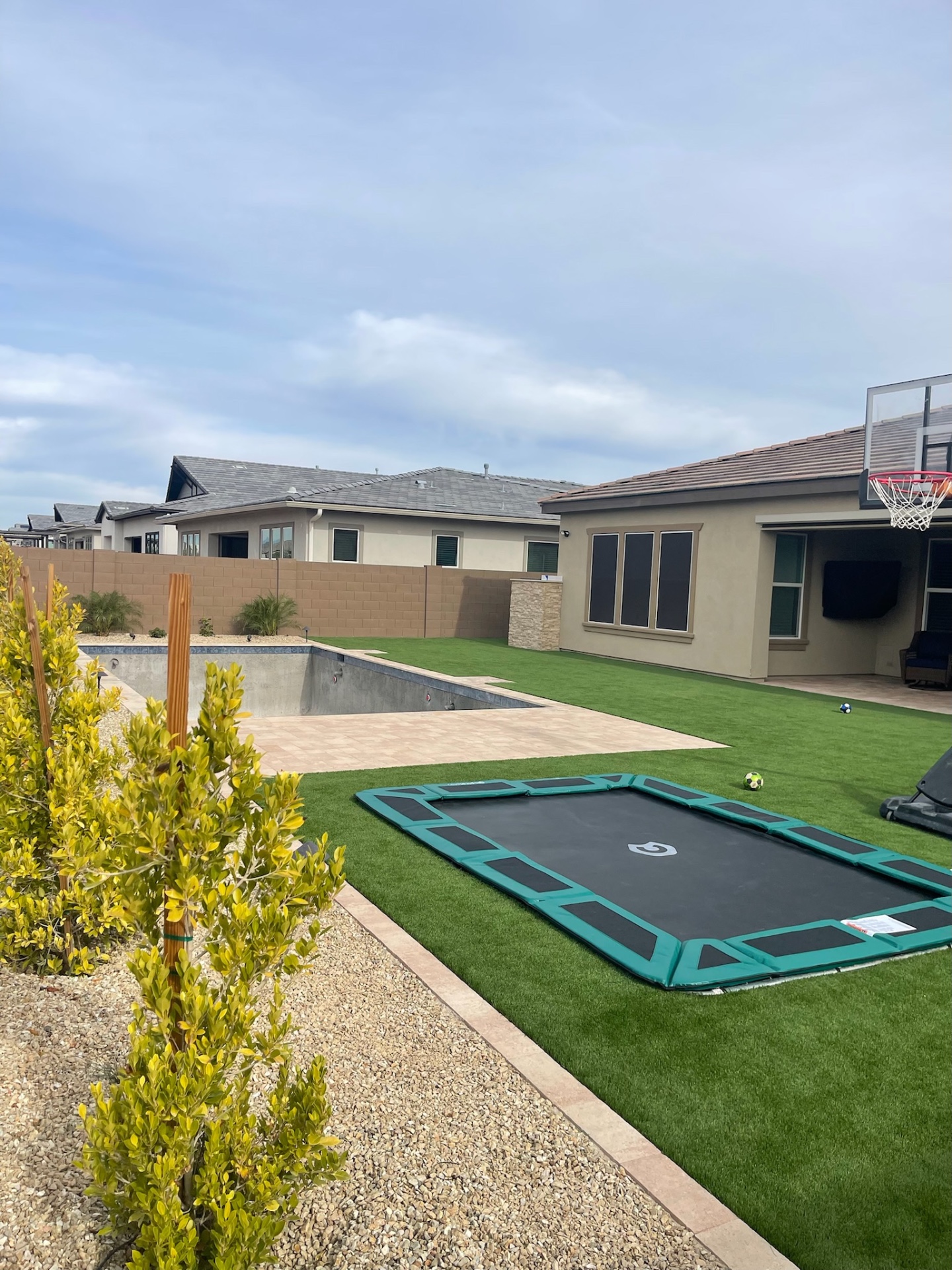 Peoria pool construction shell with travertine paver walkway, fresh artificial turf lawn and in-ground trampoline by AE Outdoor Living