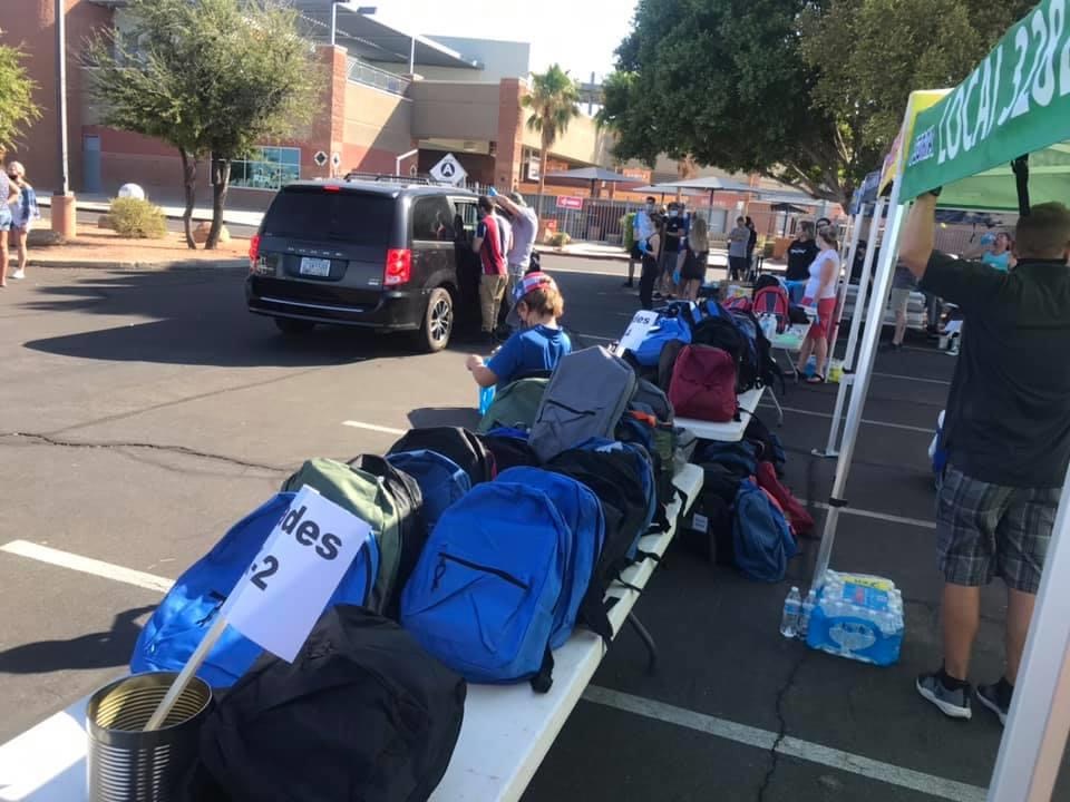Drive-through backpack distribution in a parking lot with volunteers loading a minivan