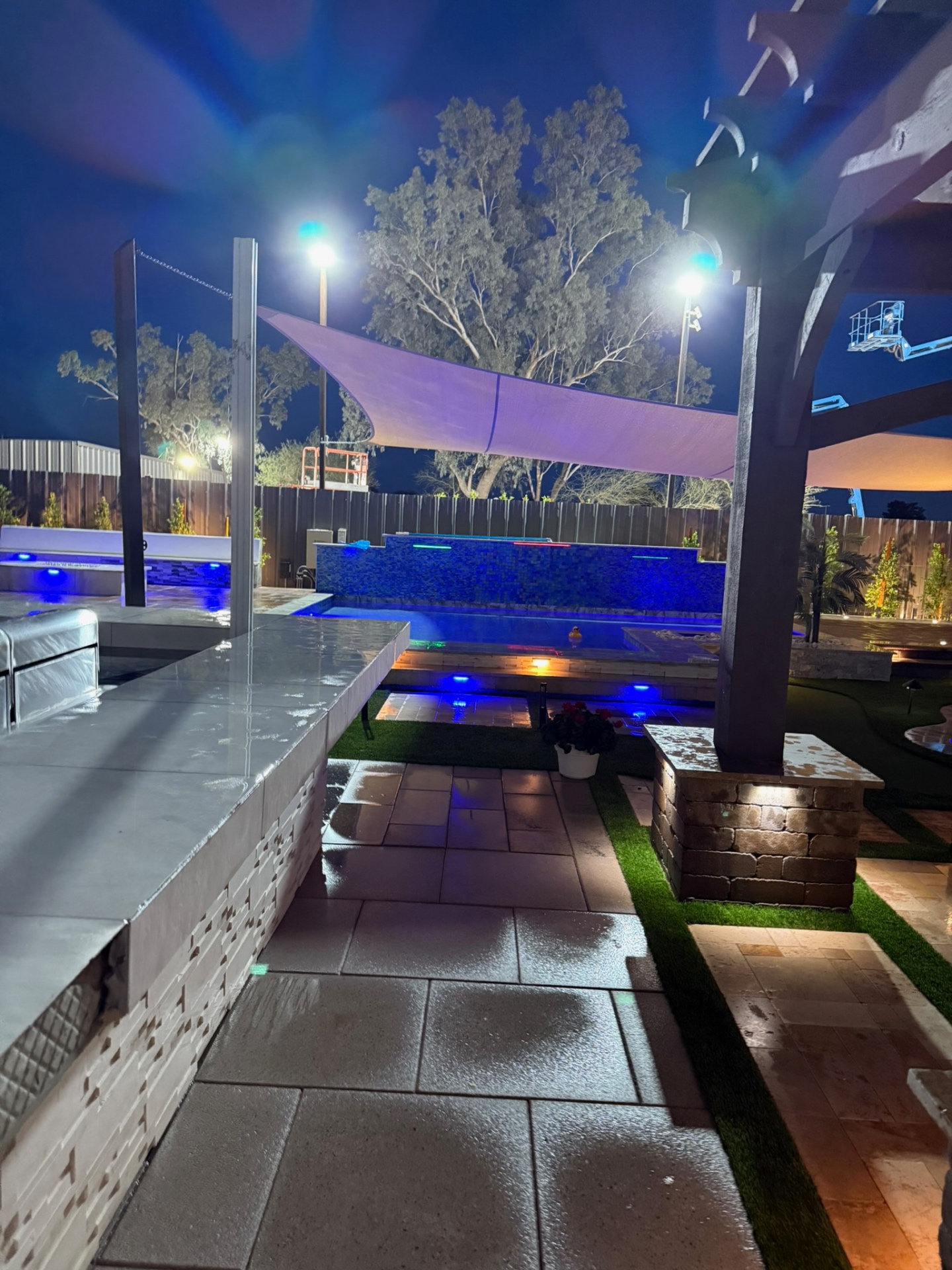 Outdoor kitchen counter overlooking pool display under shade sails