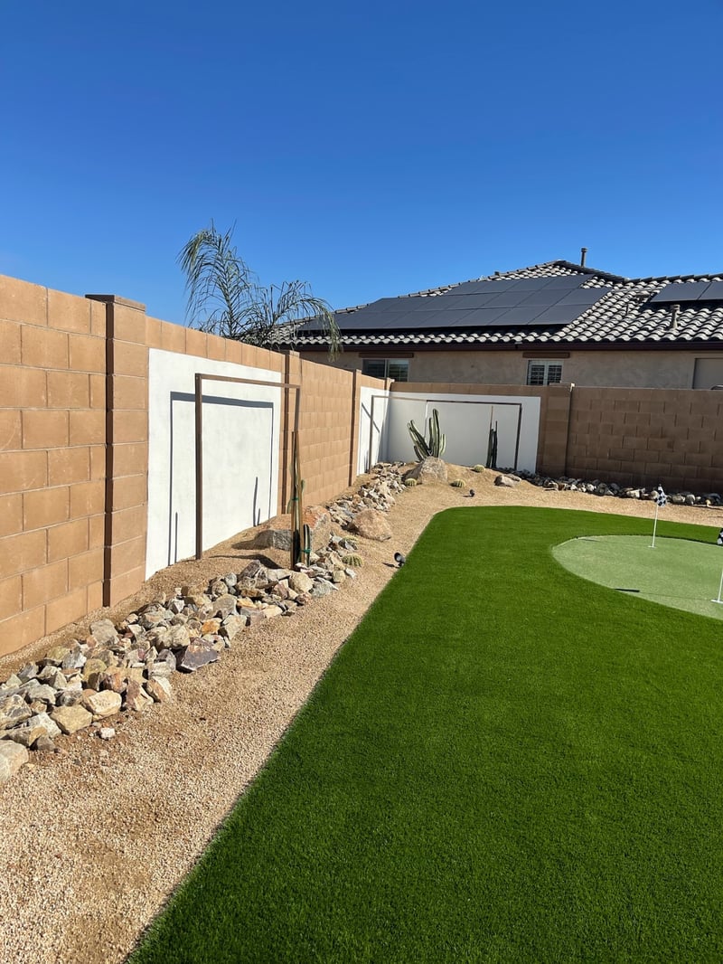 Goodyear backyard artificial turf lawn with putting green, cactus and boulder desert border along block wall