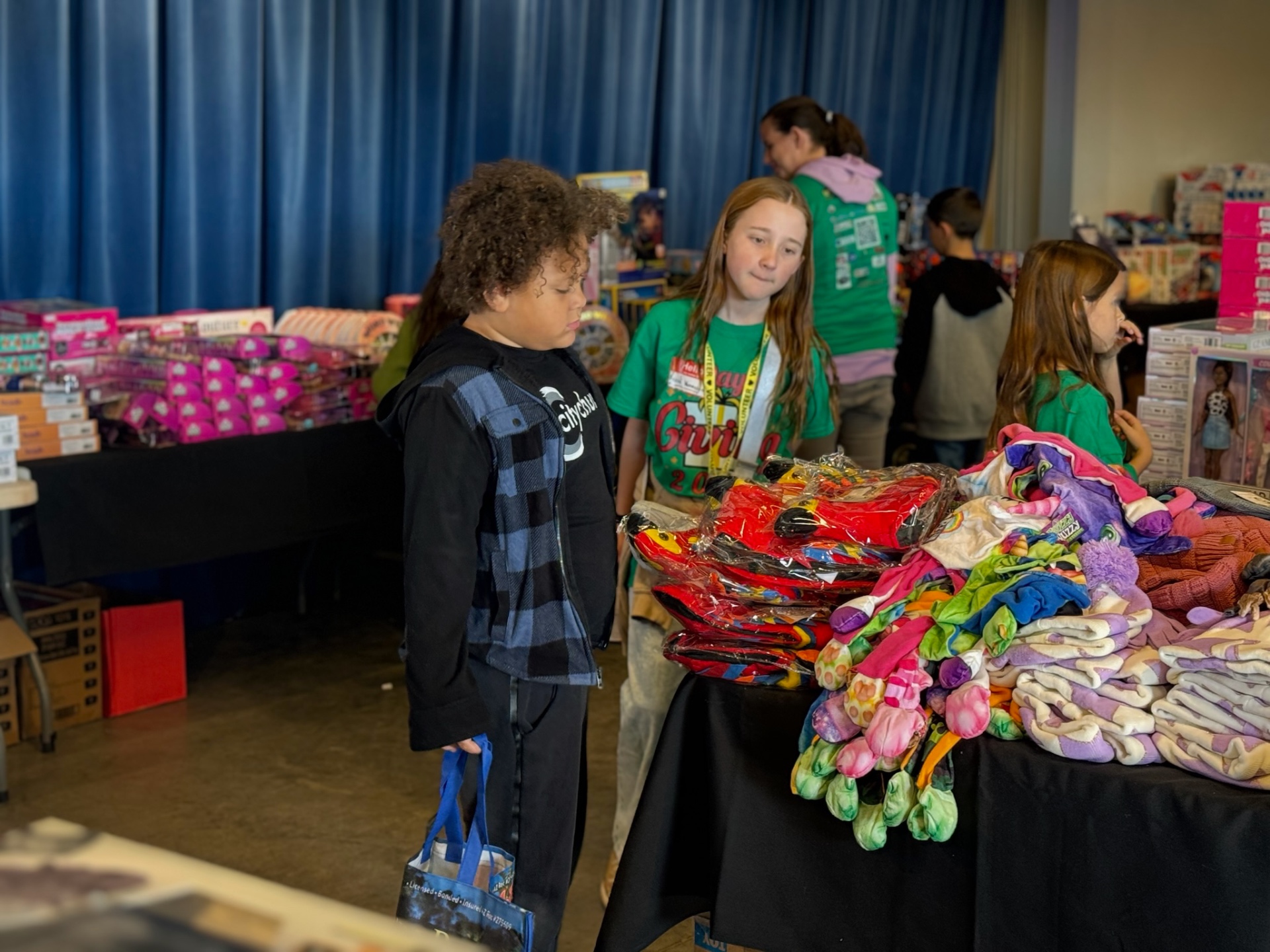 Kids picking out toys and blankets at the indoor giveaway tables during A Day of Giving 2025