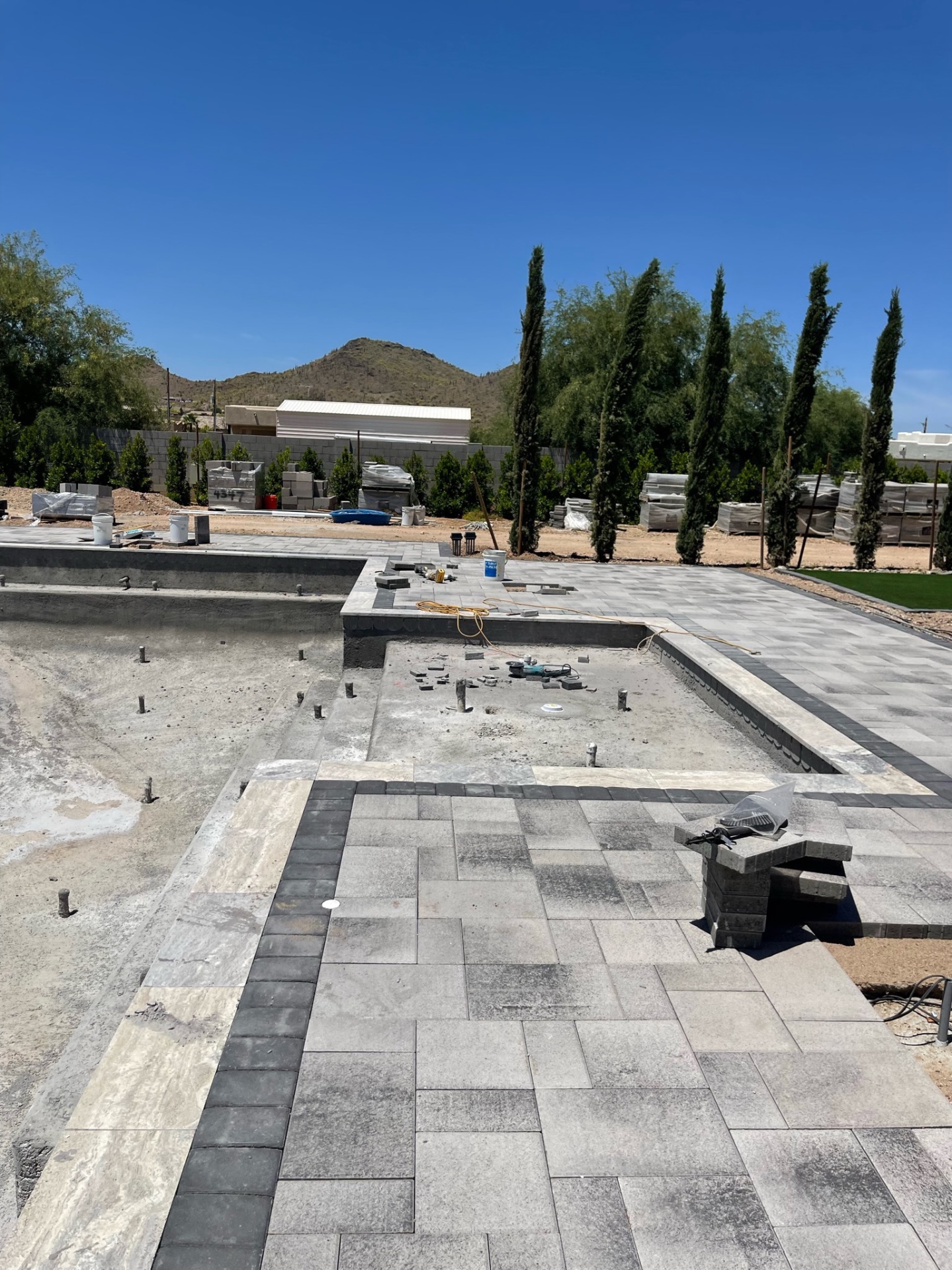 Another wide angle over the near-finished shell and paver deck with the full backyard opening toward the mountain view