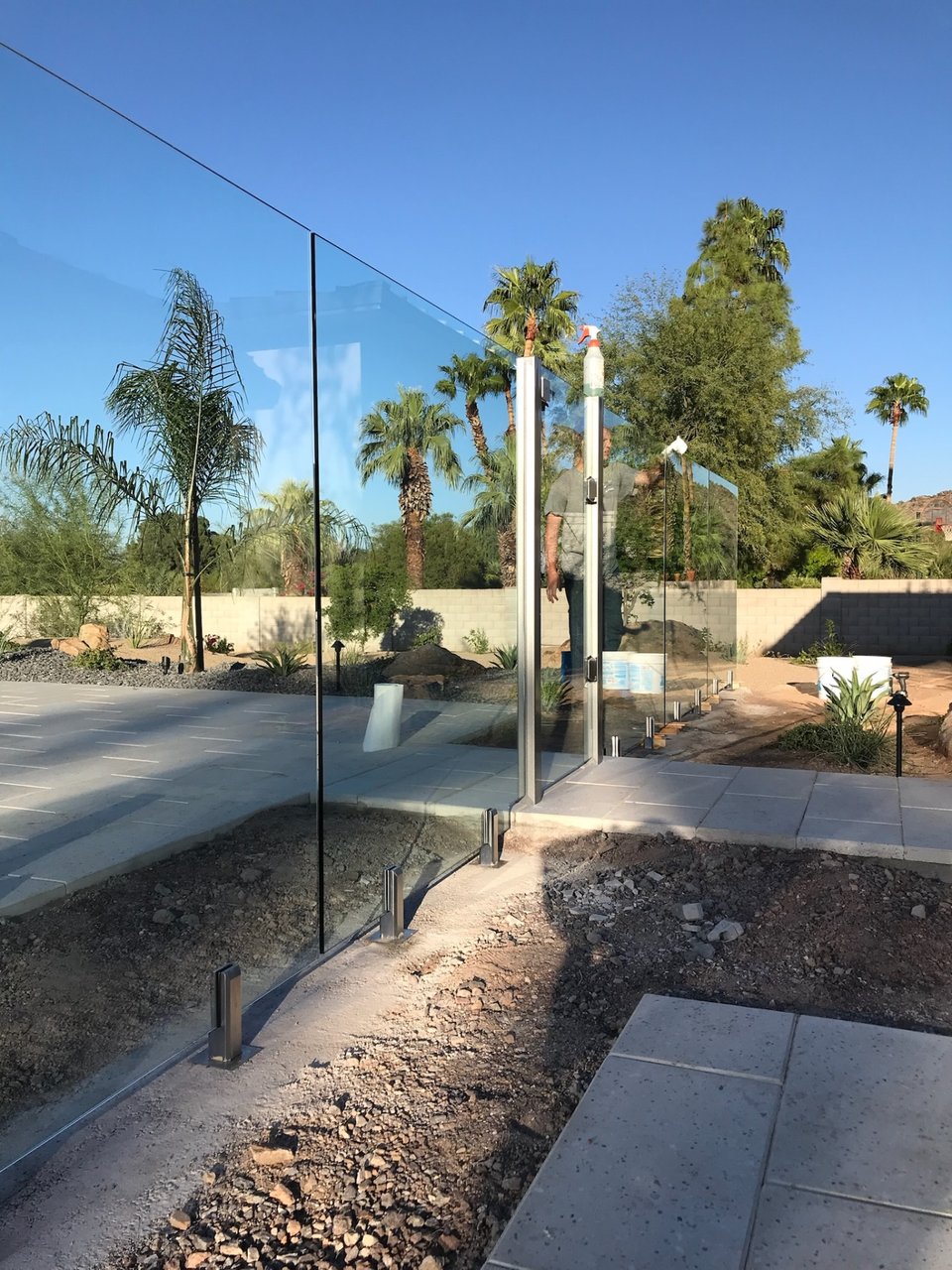 A worker squeegeeing a frameless glass gate panel during cleanup on a glass fencing project.
