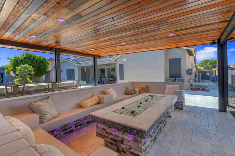 Built-in seating arranged around a rectangular fire feature beneath the Litchfield Park pavilion.
