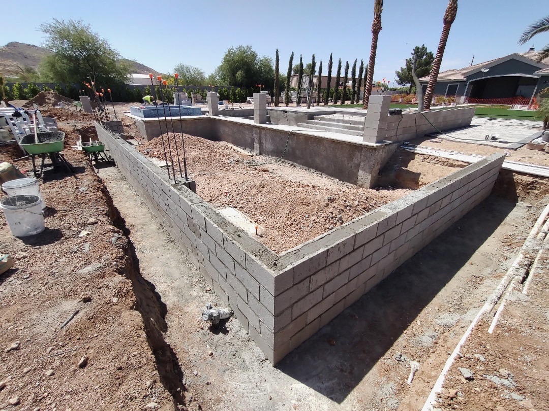 Raised planter wall with vertical rebar awaiting cell-fill, gunite pool shell behind