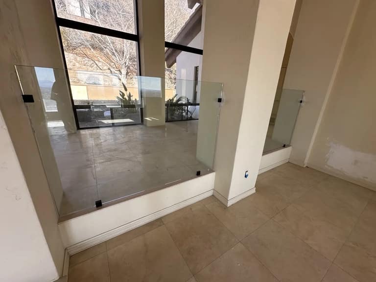 Interior glass guard panels with black base clips separating floor levels inside a Phoenix home.