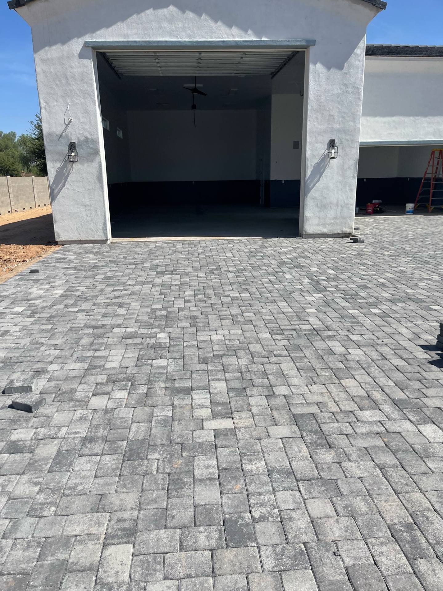 Waddell (Surprise-area) front approach to detached RV garage paved in charcoal-blend interlocking pavers with clean soldier-course border alignment by AE Outdoor Living