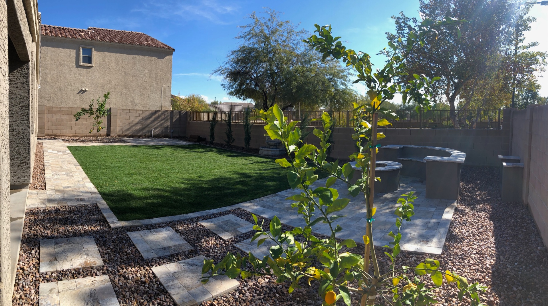 Verrado backyard with turf lawn, travertine paver stepping stones and fire-pit seating area