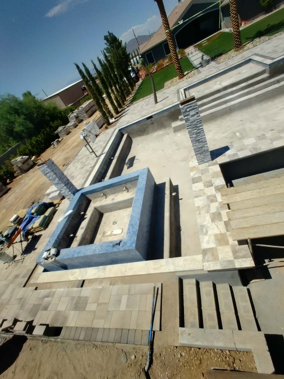 Overhead view of raised tiled spa with travertine coping, mosaic interior, and surrounding paver deck