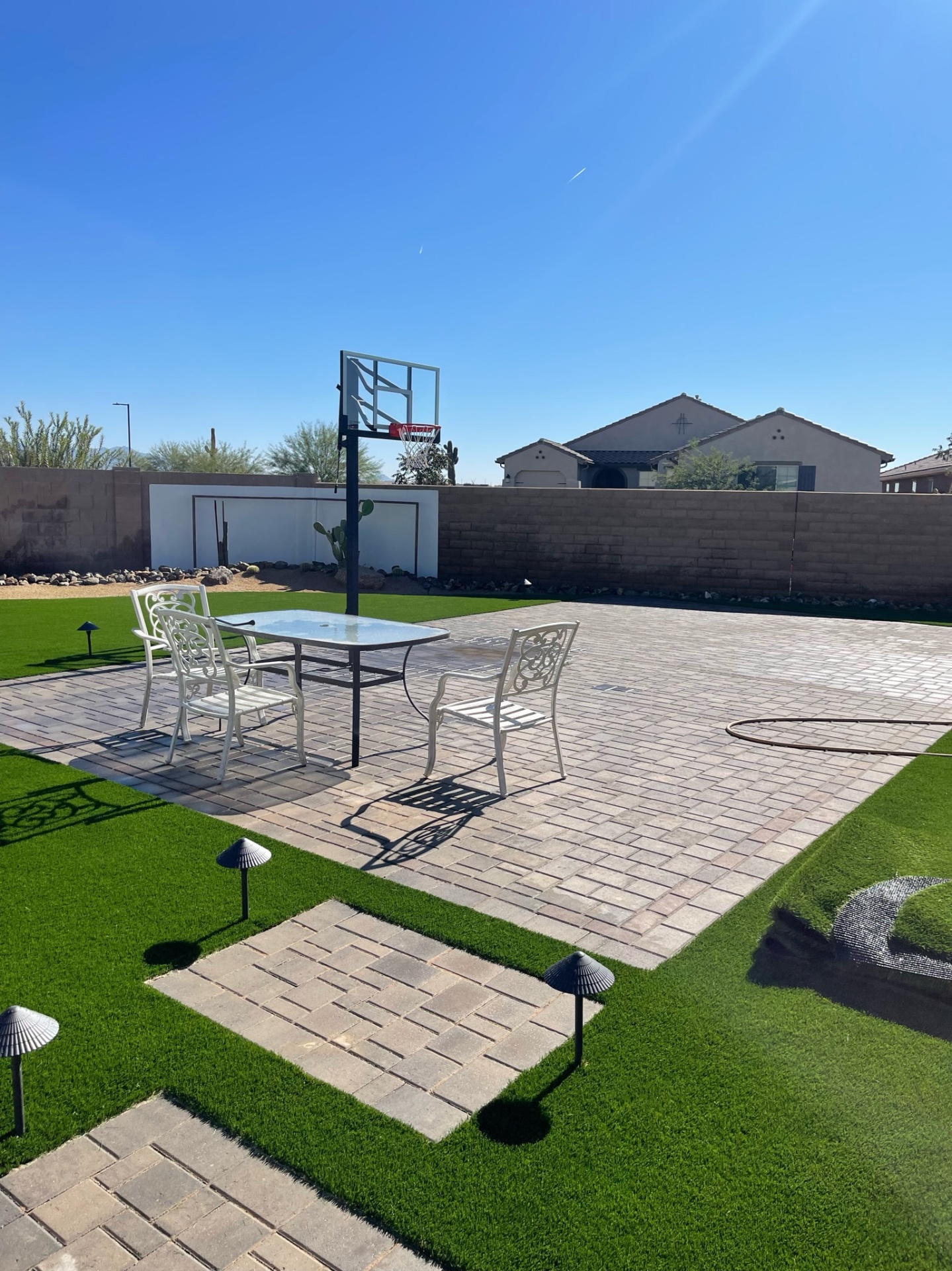 Goodyear backyard paver sport court with in-ground basketball hoop, dining set and artificial turf lawn with paver stepper path