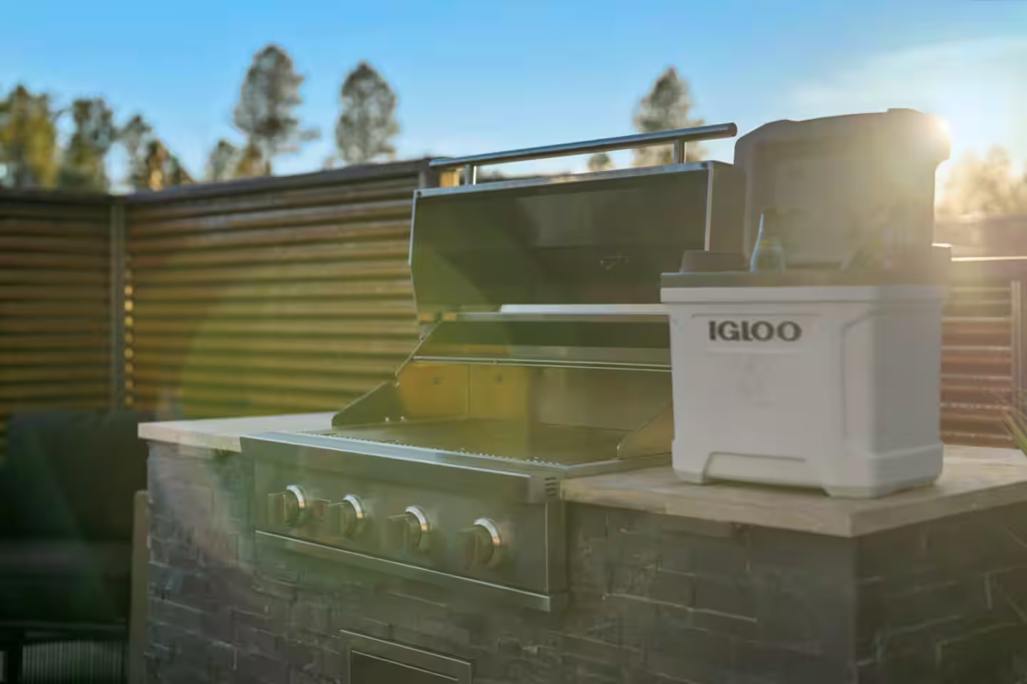 Built-in outdoor kitchen with BBQ island, stone veneer, counter, storage, and low-voltage lighting