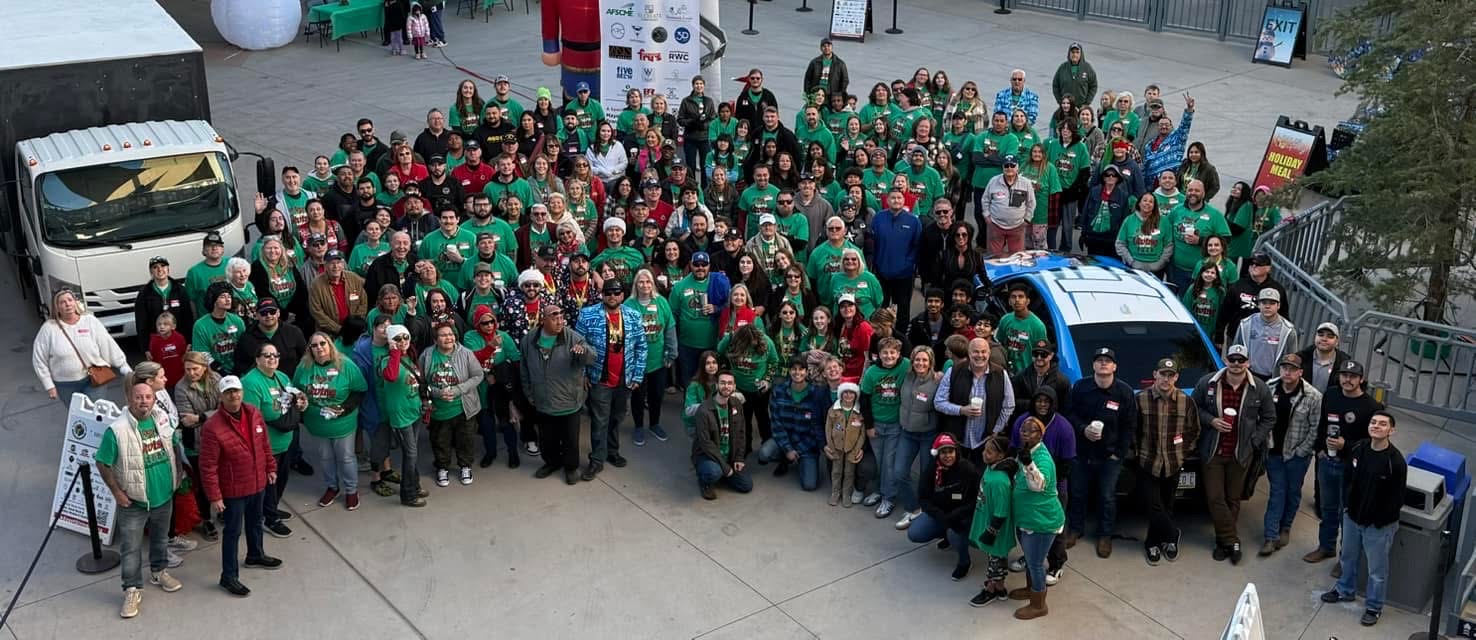 Aerial group photo of volunteers and sponsors in green shirts at A Day of Giving 2025 at Peoria Sports Complex