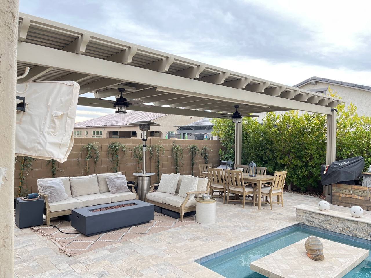 Vask residence The Meadows Peoria AZ tan alumawood lattice pergola with ceiling fans over travertine patio, sectional lounge, and teak dining set beside pool
