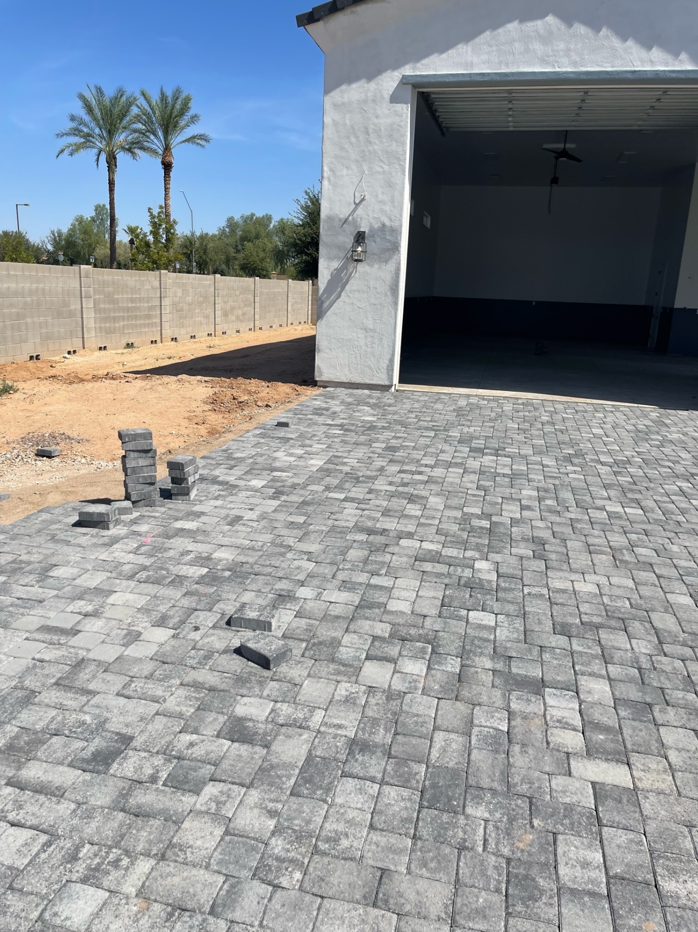 Waddell (Surprise-area) side approach along detached RV garage showing charcoal paver field extending to the block wall on a large custom-home lot by AE Outdoor Living