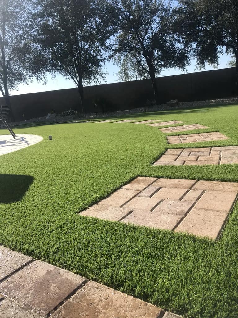 Close view of square paver stepping pads set into artificial turf in a Glendale backyard.